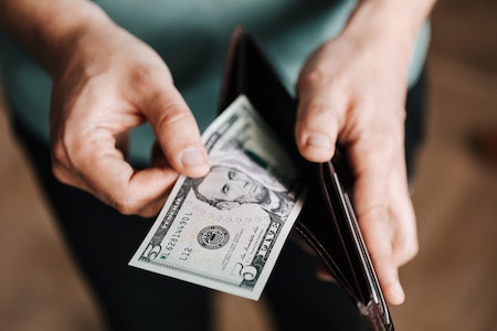 Unrecognizable man holding wallet with money - best paying jobs in public utilities