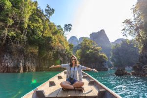 last minute vacation deals featured image woman on boat in beautiful scenery
