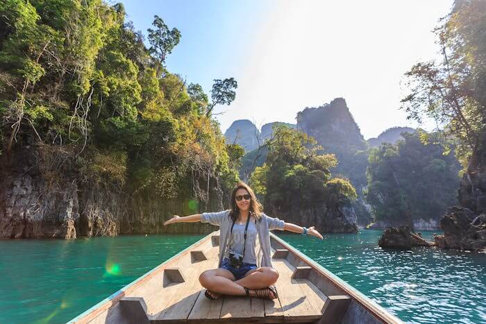 last minute vacation deals featured image woman on boat in beautiful scenery